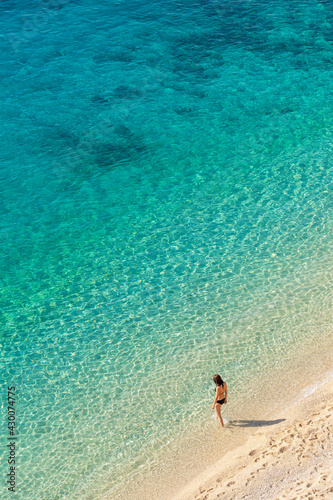 Fototapeta Naklejka Na Ścianę i Meble -  Young woman enter transparent turquoise water of the Mediterranean sea