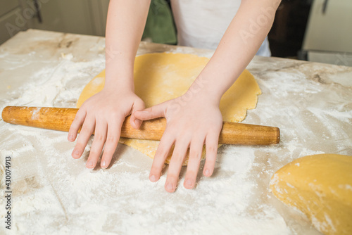 Child hands of a chef who rolls the dough at home in the kitchen. Cooking at home