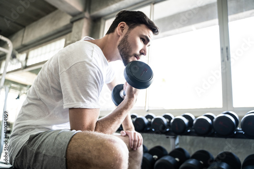 Sport man lifting up dumbbell sitting in private sport gym