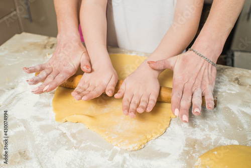 Hands of mom and son who roll out the dough in the kitchen. Cooking at home © Павел Костенко