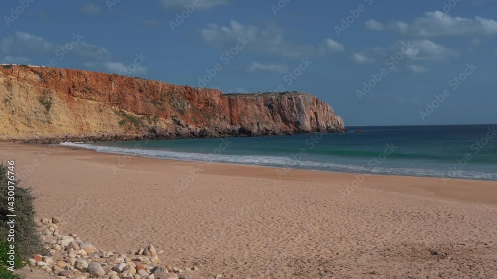 Field Landscape of a beach, with the foamy white waves breaking on the white sand, surrounded by cliffs. On a summer day with a blue sky and clouds. No people. Field Landscape of a beach, with the foamy white waves breaking on the white sand, surrounded by cliffs. On a summer day with a blue sky and clouds. No people.