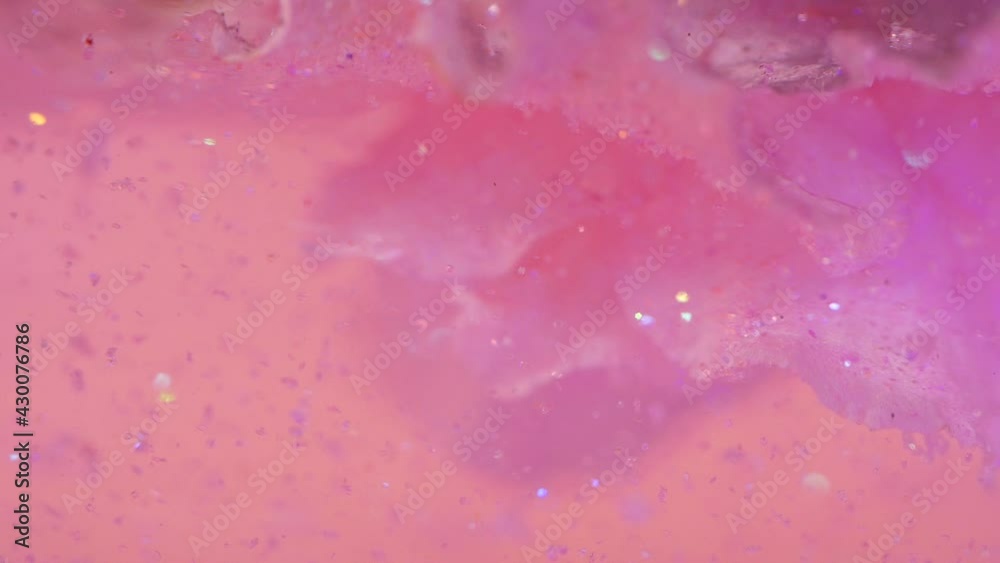 Slow motion closeup of beautiful pink flower and glitter particles under water