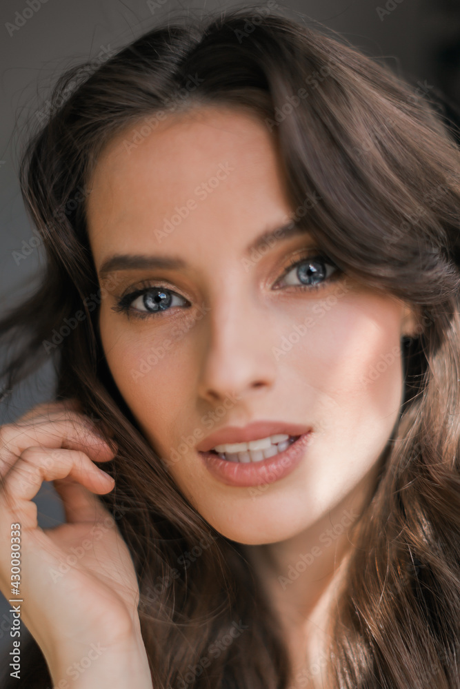 Portrait of a young brunette woman, model, enchanted look, looks at the camera, picks up hair. Portrait of a young brunette woman, model, enchanted look, looks at the camera, picks up hair.