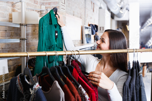 Portrait of young woman customer choosing shirt in the fashion store