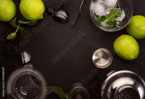 Bar tools. Ingredients for mojito cocktail with lime, mint leaves, ice. Cold drink and beverages preparation. Black table, top view with copy space