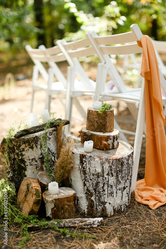 White candles near chairs in garden on wedding ceremony place. photo