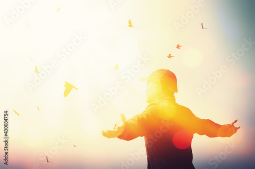 Freedom feel good and travel adventure concept. Copy space of silhouette man rising hands on sunset sky at top of mountain and bird fly abstract background.