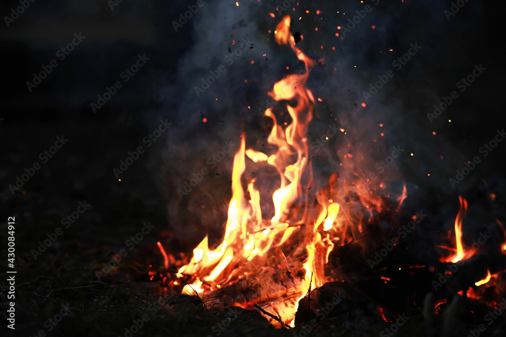 Burning red hot sparks fly from big fire. Burning coals, flaming particles flying off against black background. Burning red hot sparks fly from big fire. Burning coals, flaming particles flying off against black background.