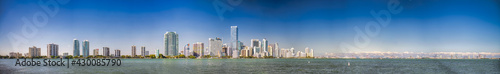 Panoramic view of Downtown Miami, Miami Beach Skyline and city port from Rickenbacker Causeway at sunset, with two airplanes in the sky © jovannig