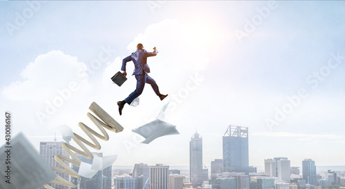 Businessman jumping on springboard . Mixed media photo
