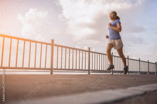 Fototapeta Naklejka Na Ścianę i Meble -  A woman jogging on the bridge. Healthy lifestyle fitness woman. Concept of running and fitness for health.