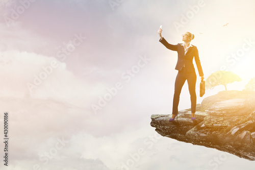 Businesswoman standing against landscape and making selfie