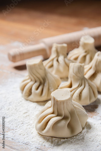 Georgian dumplings Khinkali with meat, on a wooden board with flour, black background.