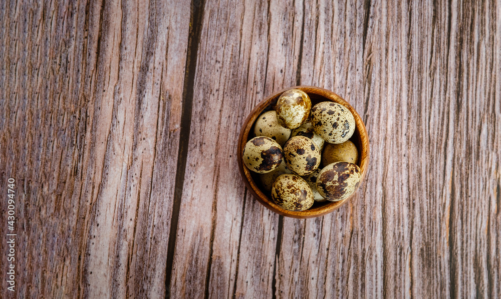 Quail eggs in a wooden bowl on a wooden background. Sweets. Easter