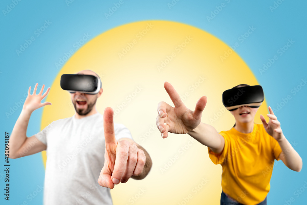 Naklejka premium People wearing virtual reality glasses reach for a virtual object with their hands. Blurred. Blue background with a yellow circle. The concept of virtual reality and modern technologies