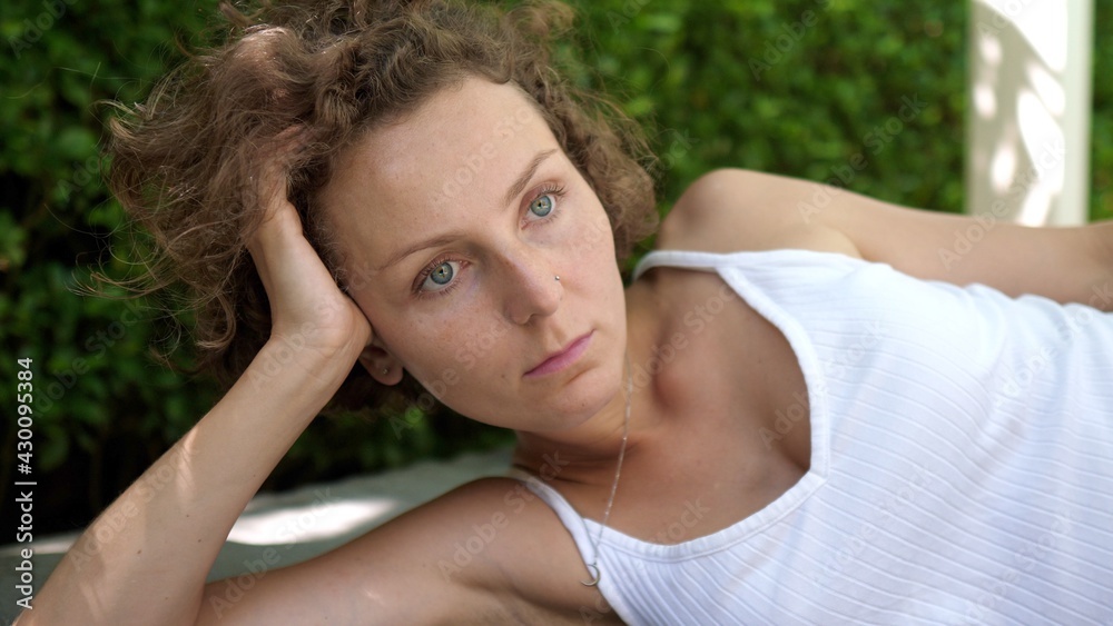 Portrait of a pensive girl laying leaning on her arm outside in the sun Portrait of a pensive girl laying leaning on her arm outside in the sun