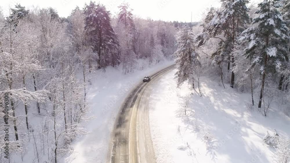 Aerial view overlooking a road, in middle of snow covered trees and snowy forest Aerial view overlooking a road, in middle of snow covered trees and snowy forest