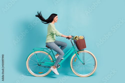 Fototapeta Naklejka Na Ścianę i Meble -  Profile side view of attractive cheerful girl riding bike having fun air blowing hair isolated over bright blue color background