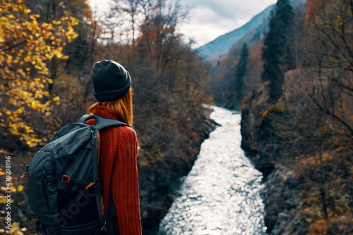woman tourist with backpack admires nature river mountains travel