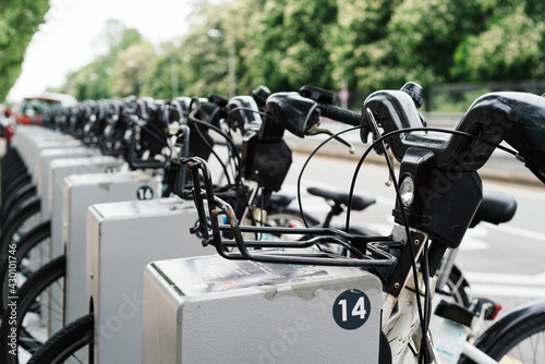 Row of bicycles parked. White bicycles stand on a parking for rent in a bicycle rental service spot on city street. Public transportation concept. Save energy and environmentally friendly. 