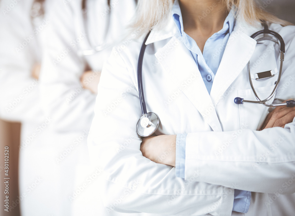 Group of modern doctors standing as a team with arms crossed in sunny hospital and ready to help patients. Medical help, insurance in health care Group of modern doctors standing as a team with arms crossed in sunny hospital and ready to help patients. Medical help, insurance in health care