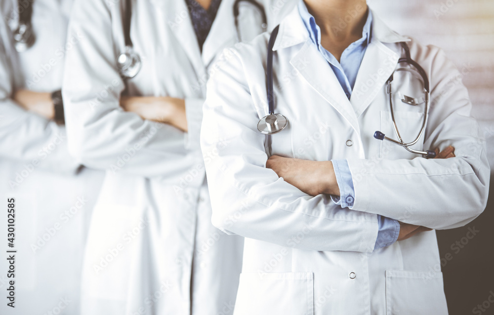 Group of modern doctors standing as a team with arms crossed in sunny hospital and ready to help patients. Medical help, insurance in health care Group of modern doctors standing as a team with arms crossed in sunny hospital and ready to help patients. Medical help, insurance in health care