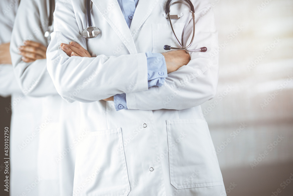 Group of modern doctors standing as a team with arms crossed in sunny hospital and ready to help patients. Medical help, insurance in health care Group of modern doctors standing as a team with arms crossed in sunny hospital and ready to help patients. Medical help, insurance in health care