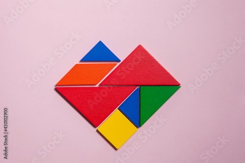 Heart of colorful tangrams in pink background 