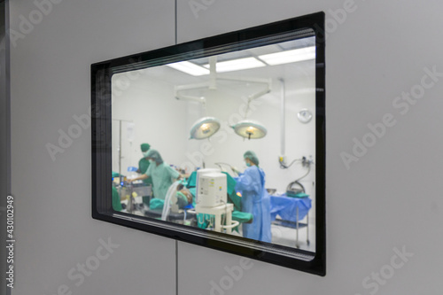 Selective focus team of doctor doing operation using medical equipment. Group of surgeons in operating room with surgery equipment. Medical background. View from the window to the operating room.