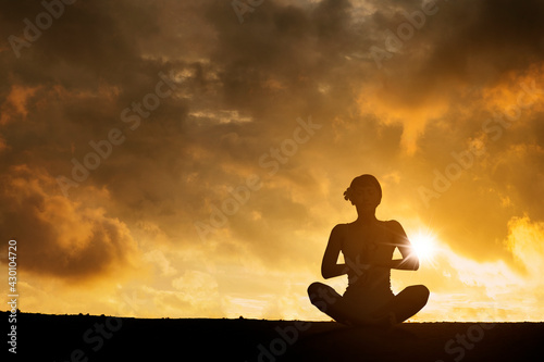 Silhouette of woman doing yoga exercise on hills © Creativa Images