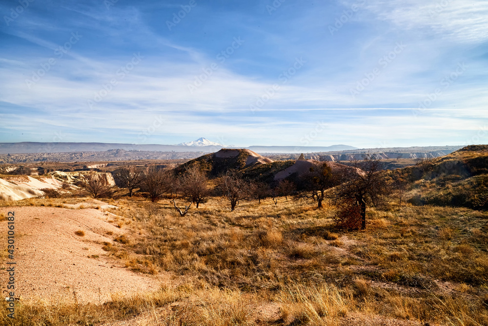 View of the landscape in the Cappadocia valley with strange yellow mountains, rocks and hills and blue sky View of the landscape in the Cappadocia valley with strange yellow mountains, rocks and hills and blue sky