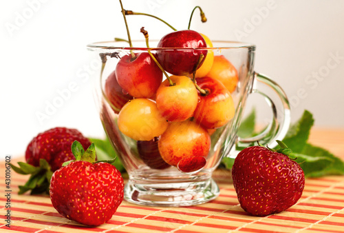 bright ripe yellow and red cherries in a glass bowl with strawberries  healthy nutrition concept  poster with organic fruit and berries