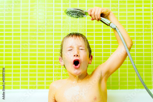 Fotografia Funny expression of a boy portrayed when taking a shower and pouring water down his face to clean his hair, yellow background