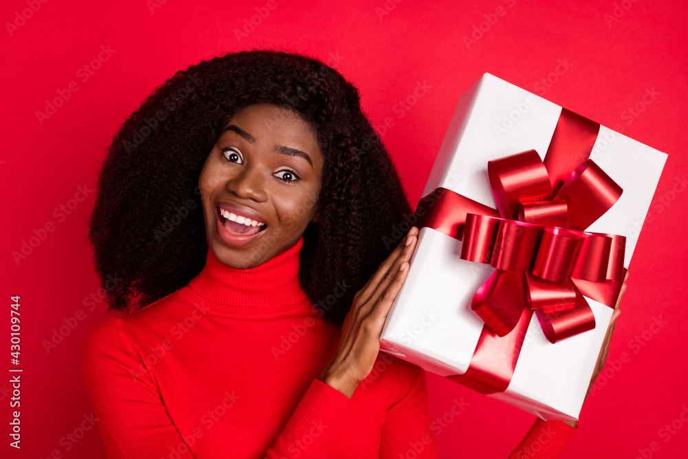 Photo of young black woman happy positive smile hold present box birthday party isolated over red color background Photo of young black woman happy positive smile hold present box birthday party isolated over red color background