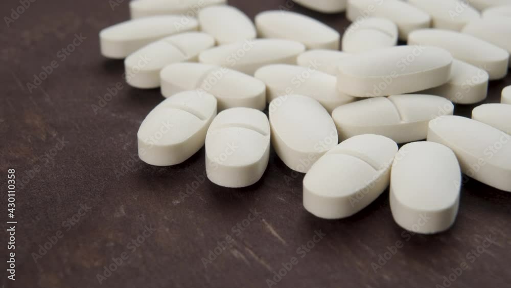 White medical pills on a dark brown board close-up. Macro. Dolly Shot White medical pills on a dark brown board close-up. Macro. Dolly Shot