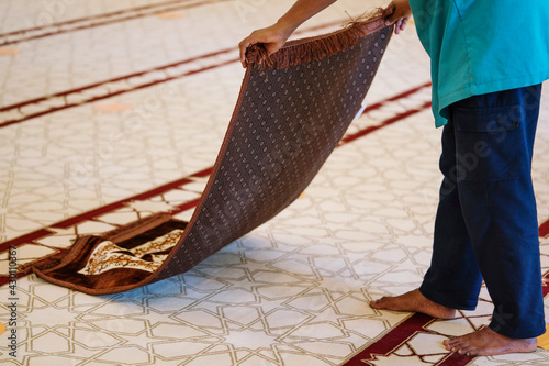 Muslim man holding his praying mat during pray time in the mosque
