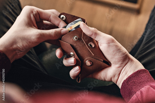 The man takes out discount cards from a leather card holder with buttons. Close-up, no face, horizontal orientation, copy space, top view