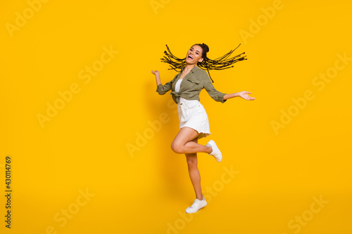 Full length photo portrait of girl dancing standing on one leg isolated on vivid yellow colored background © deagreez