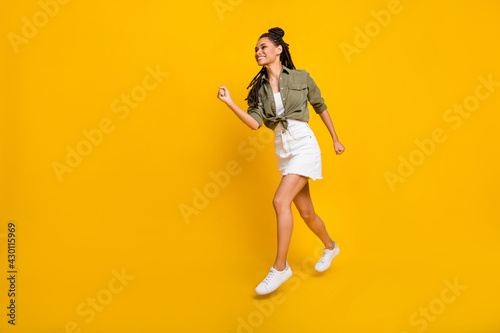 Photo portrait full body view of dark skin woman running isolated on vivid yellow colored background with blank space