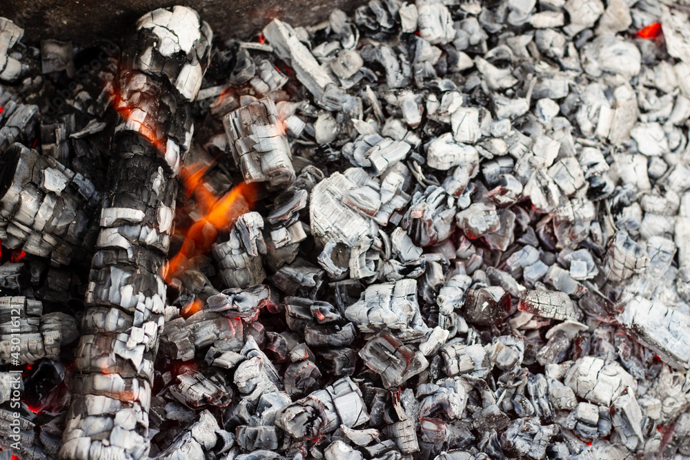 Burning coal in a barbecue. Beautiful texture of burnt firewood and coals in a campfire with bright fire for a barbecue close up