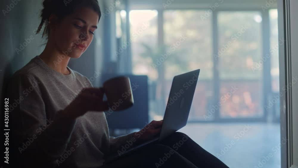 Portrait of Young Woman Using Laptop at Home. Beautiful Girl Sitting on a Floor Uses Internet, Does Remote Work, Drinking Morning Cup of Coffee. Mellow Atmosphere of Productive Work, Social Media Use Portrait of Young Woman Using Laptop at Home. Beautiful Girl Sitting on a Floor Uses Internet, Does Remote Work, Drinking Morning Cup of Coffee. Mellow Atmosphere of Productive Work, Social Media Use