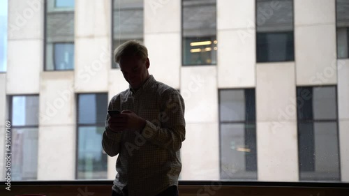 rear view of mature business man standing by window in office and looking at modern buildings