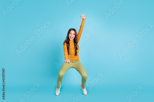 Full size photo of cheerful carefree pupil standing on tiptoe raise hand open mouth isolated on blue color background