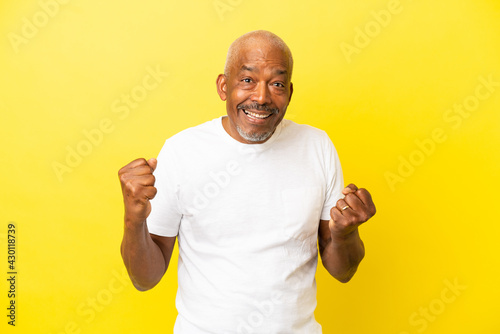 Cuban Senior isolated on yellow background celebrating a victory in winner position photo