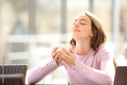 Woman holding coffee cup breathing fresh air in a bar