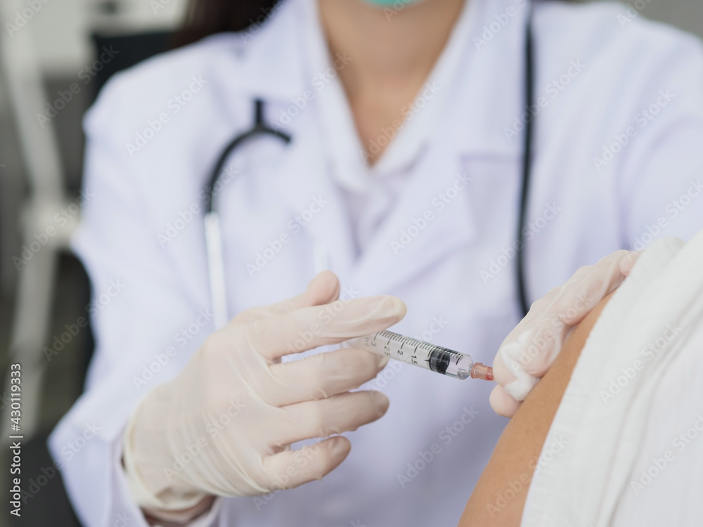A close-up of a female doctor's hand using a syringe and cotton to vaccinate a patient, a gloved hand holding a syringe to vaccinate. A close-up of a female doctor's hand using a syringe and cotton to vaccinate a patient, a gloved hand holding a syringe to vaccinate.