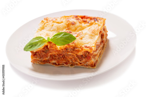 plate of lasagna with green basil on white background