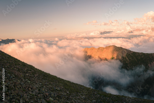The top of a mountain range surrounded by thick clouds in the evening in the Mukhinsky gorge of the Teberda nature reserve. © Ambartsumian