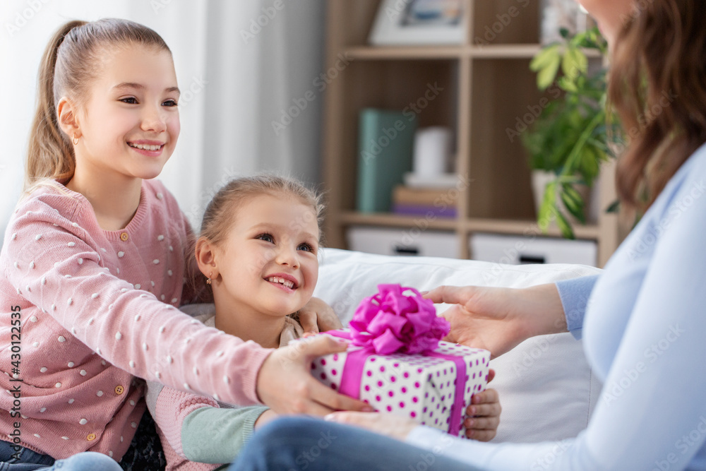 people, family and holidays concept - two daughters giving present to happy mother at home people, family and holidays concept - two daughters giving present to happy mother at home