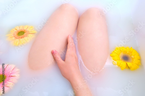 Flowers in a white bathroom and a woman legs, close-up © Андрей Журавлев